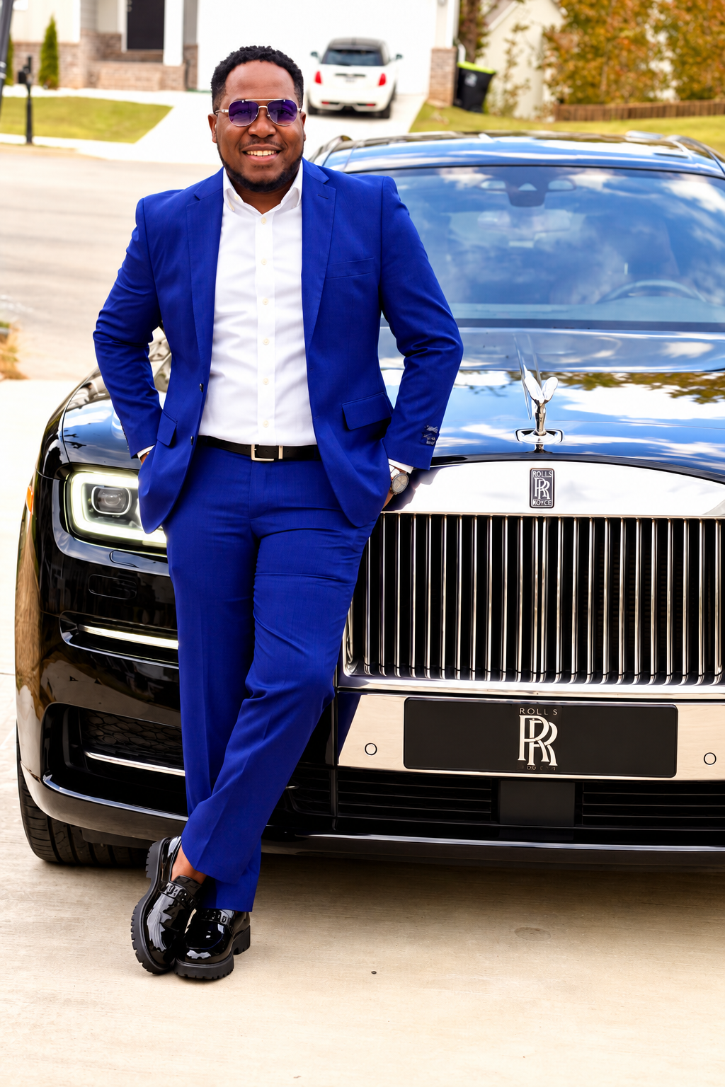 Portrait artistique de Renaud Frédéric en costume bleu devant une Rolls-Royce